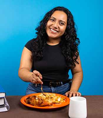 Lirio smiling standing infront of a plate of ethnic food